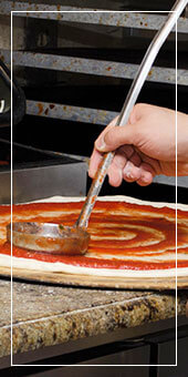 renzo's pizza man putting sauce on pizza dough
